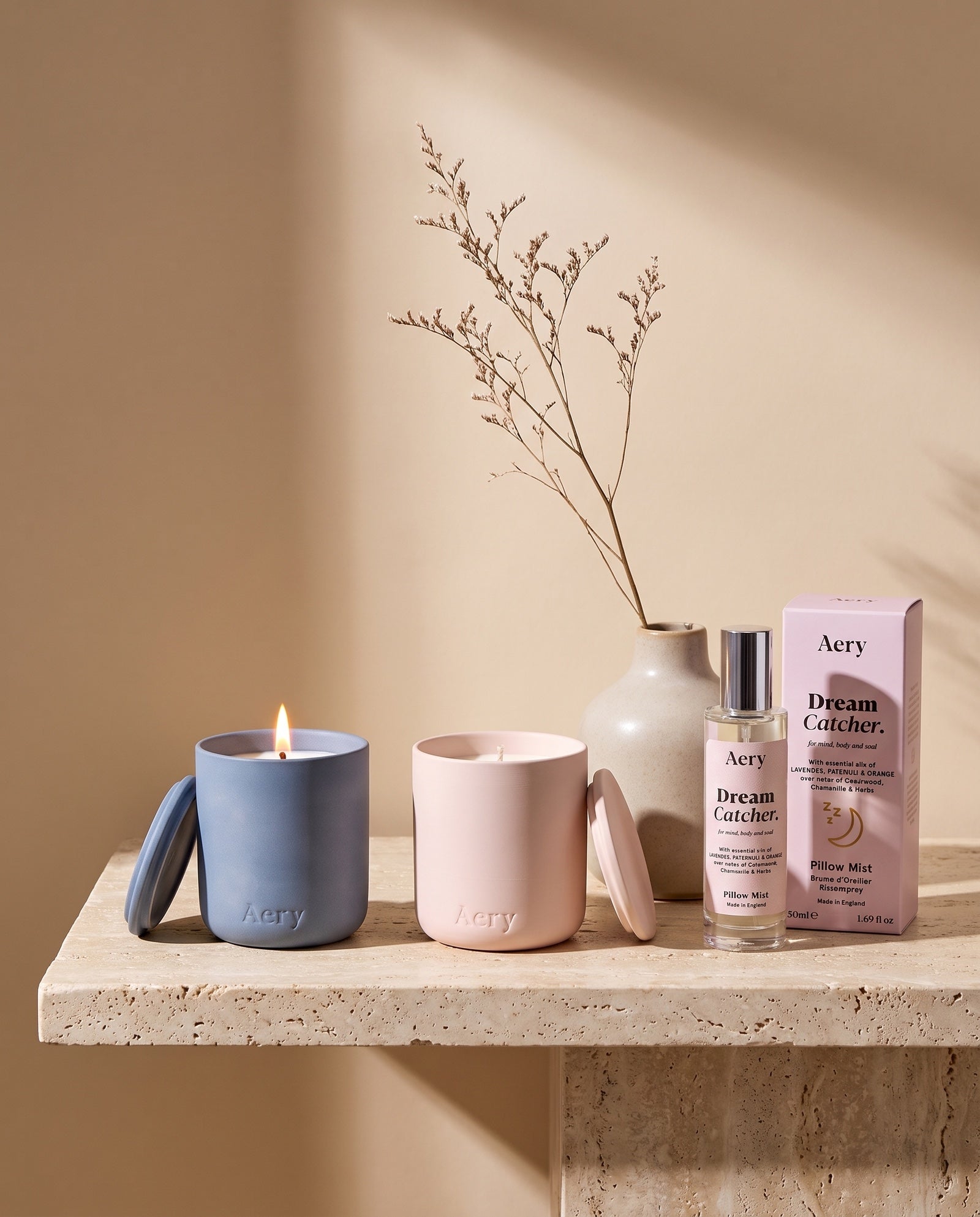 Aery candles and pillow mist on a travertine shelf