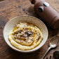 Silky mashed potatoes with truffle oil, cracked pepper and black truffle shavings in a speckled bowl