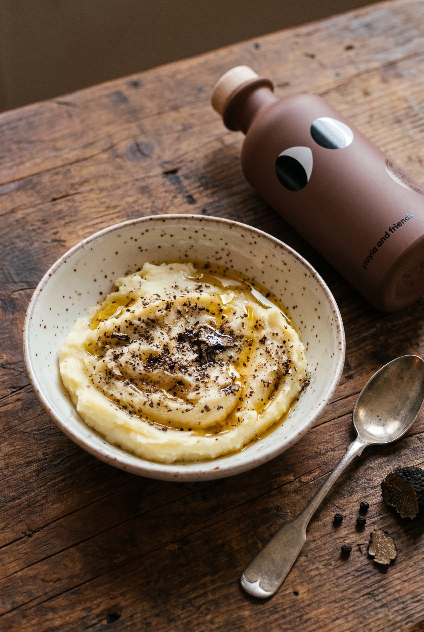 Silky mashed potatoes with truffle oil, cracked pepper and black truffle shavings in a speckled bowl