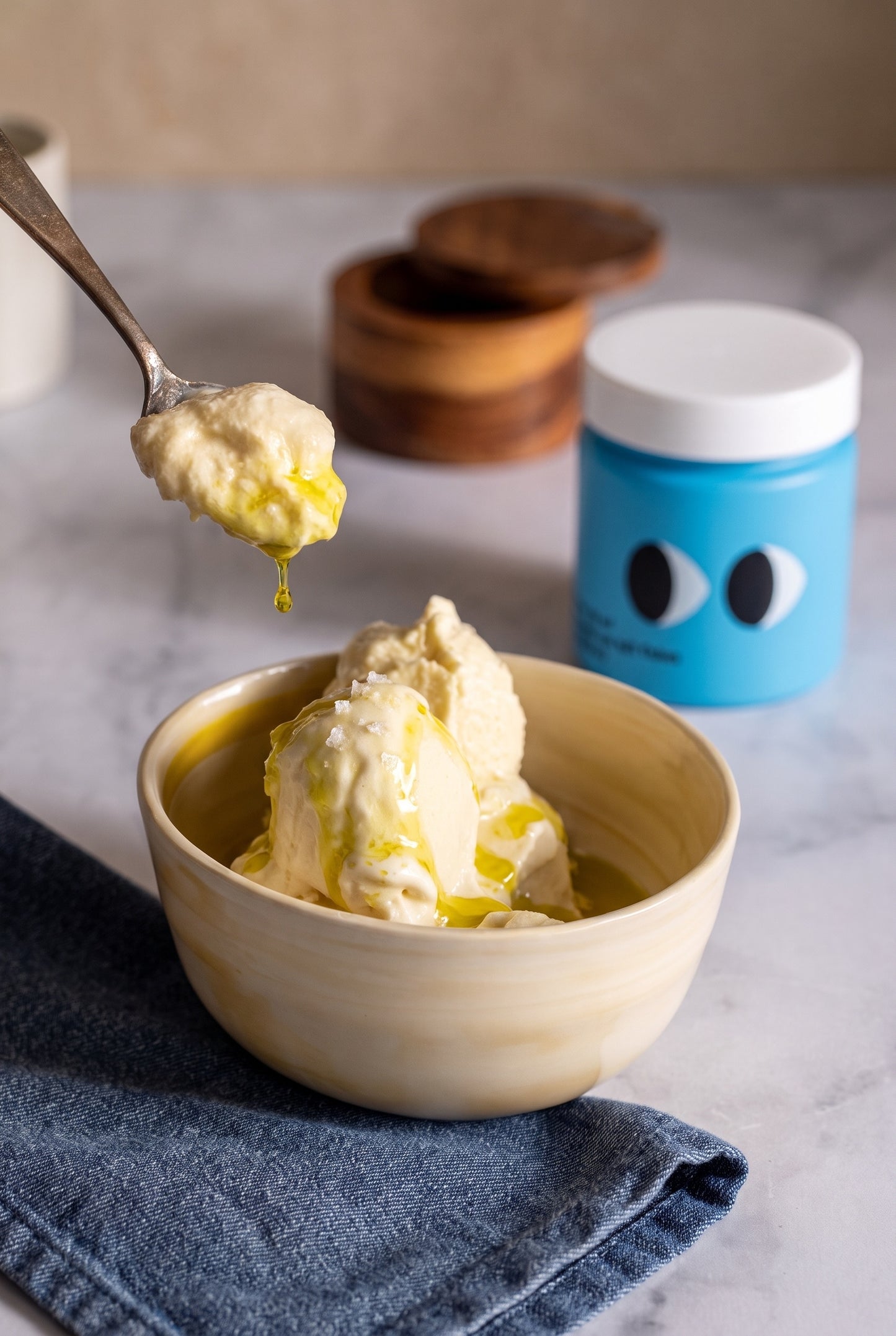 Vanilla ice cream with olive oil and sea salt flakes, a spoonful lifted above the bowl