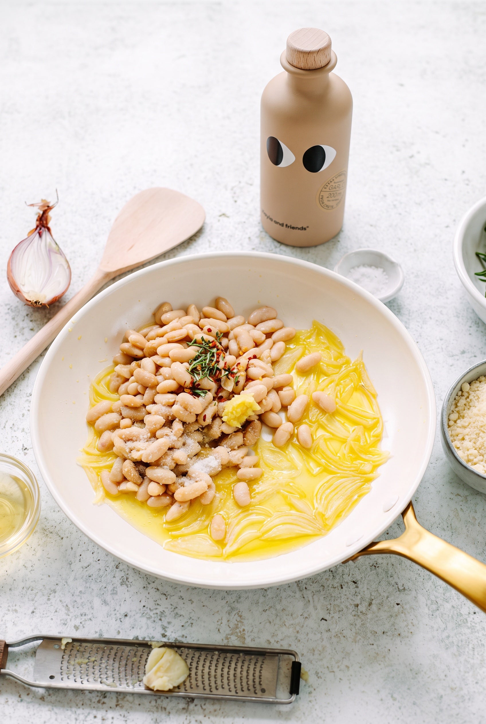 Creamy skillet white beans with melted onions, rosemary and garlic olive oil in a white pan